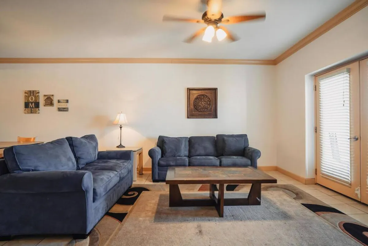 Another angle of a well-furnished living room with plush sofas, a coffee table, side lamp, and wall art. The setting is ideal for cozy conversations, relaxing with loved ones, and enjoying downtime together.