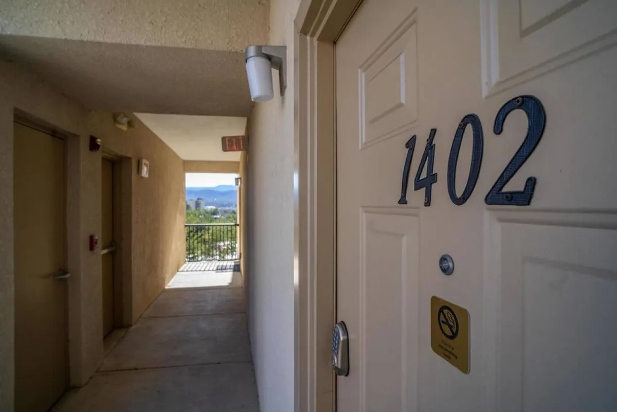 A close-up view of the entry door labeled 1402, with a modern handle and subtle wall accents. The scene suggests a welcoming first impression and the ease of entering the property, aligning with the contactless self check-in process mentioned in the section.